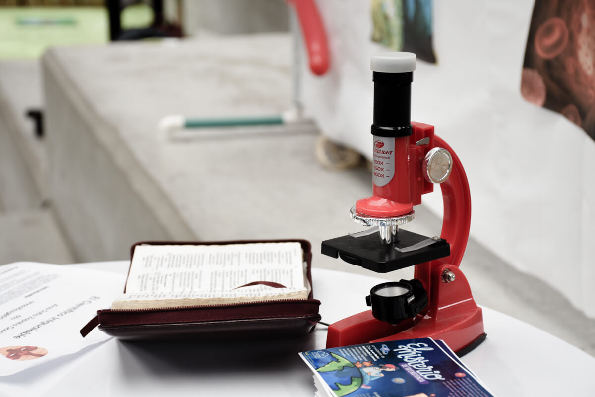 Fotografía donde se observa un microscopio y un libro sobre una mesa en una de las jornadas de la feria Cibersorprende del Cibercolegio UCN.
