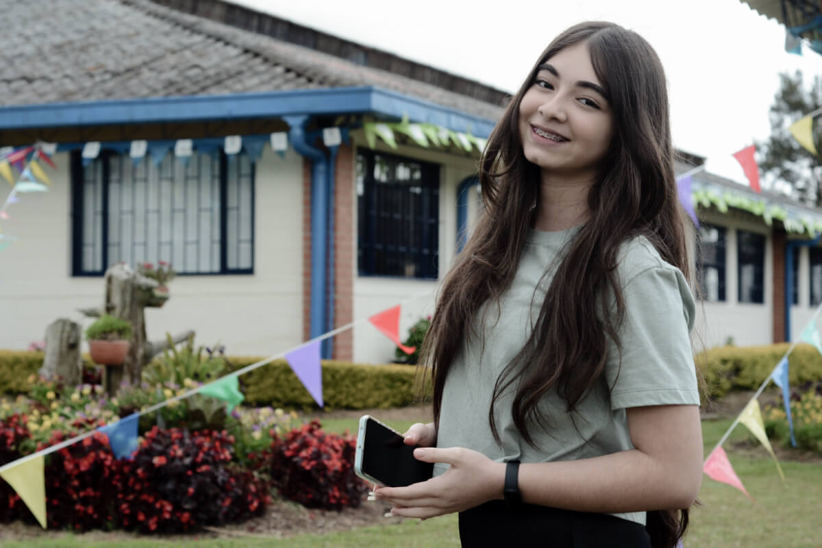 Fotografía de joven alumna del Cibercolegio UCN ubicada en la zona verde del Campus de la Fundación Universitaria Católica del Norte.
