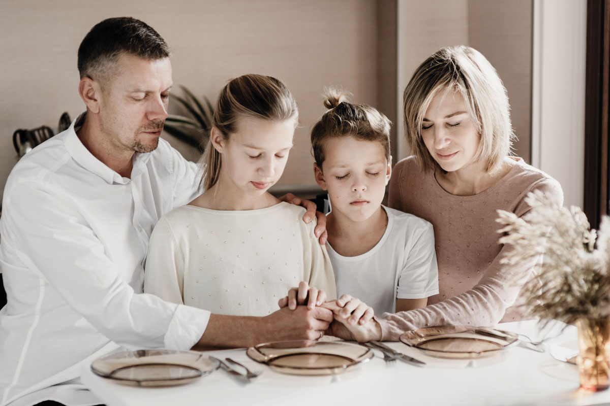 Familia, orando junta entorno a la mesa