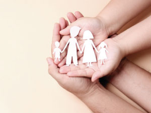 Imagen de unas manos sosteniendo la figura de una familia hecha con papel