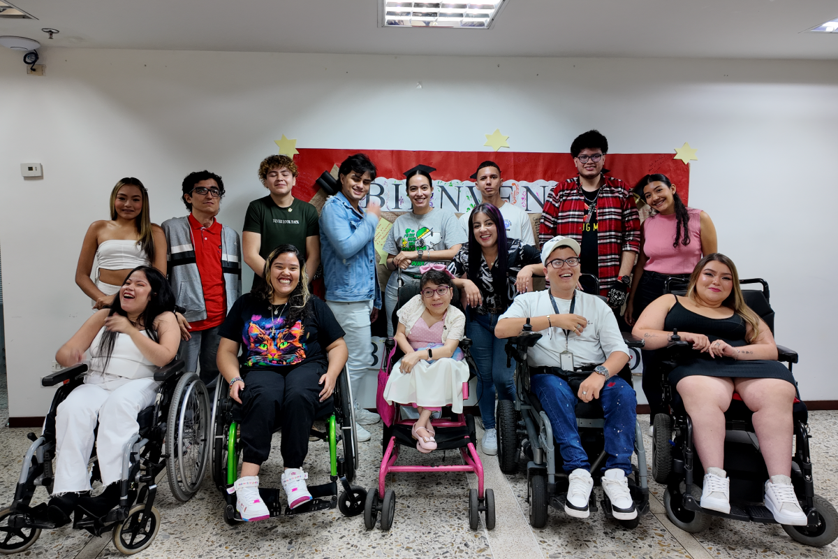 Fotografía de un grupo de graduados del Cibercolegio que usan togas y virretes. Algunos de ellos están sentados en sillas de ruedas.